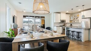 A modern kitchen with white cabinets, a large island with bar stools, and a hanging pendant light.