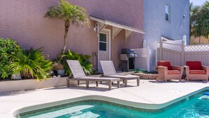 A swimming pool with lounge chairs and a small patio area. - Private Pool, Ocean View Entire Home in Beautiful New Smyrna Beach, FL. (New Smyrna Beach)