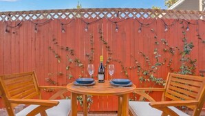 Una mesa de madera con dos sillas, una botella de vino y dos copas, dispuestas para dos comensales.