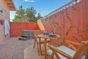 A patio with a wooden table and chairs, a barbecue grill, and a red wooden fence with vines. - Cozy Guest House Perfect For Couples w/ Hot Tub (Sedona)