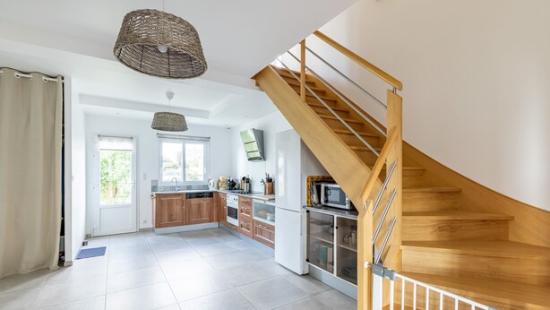 Eine moderne Küche mit Holzausstattung, einer integrierten Mikrowelle und einer Holztreppe.