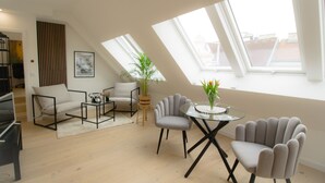A modern living room with a high ceiling and skylights, a sofa, armchairs, a coffee table, and a small side table. - Stylish & Modern Apartment (Vienna)