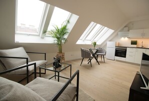 Um apartamento moderno com pé direito elevado estilo loft, grandes janelas, área de refeições e cozinha compacta.