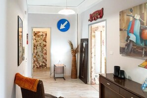 A hallway with a directional sign, a dining area with a table and chairs, and a refrigerator.