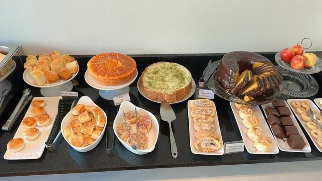 Buffet com diversos pratos, incluindo bolos, doces e frutas.