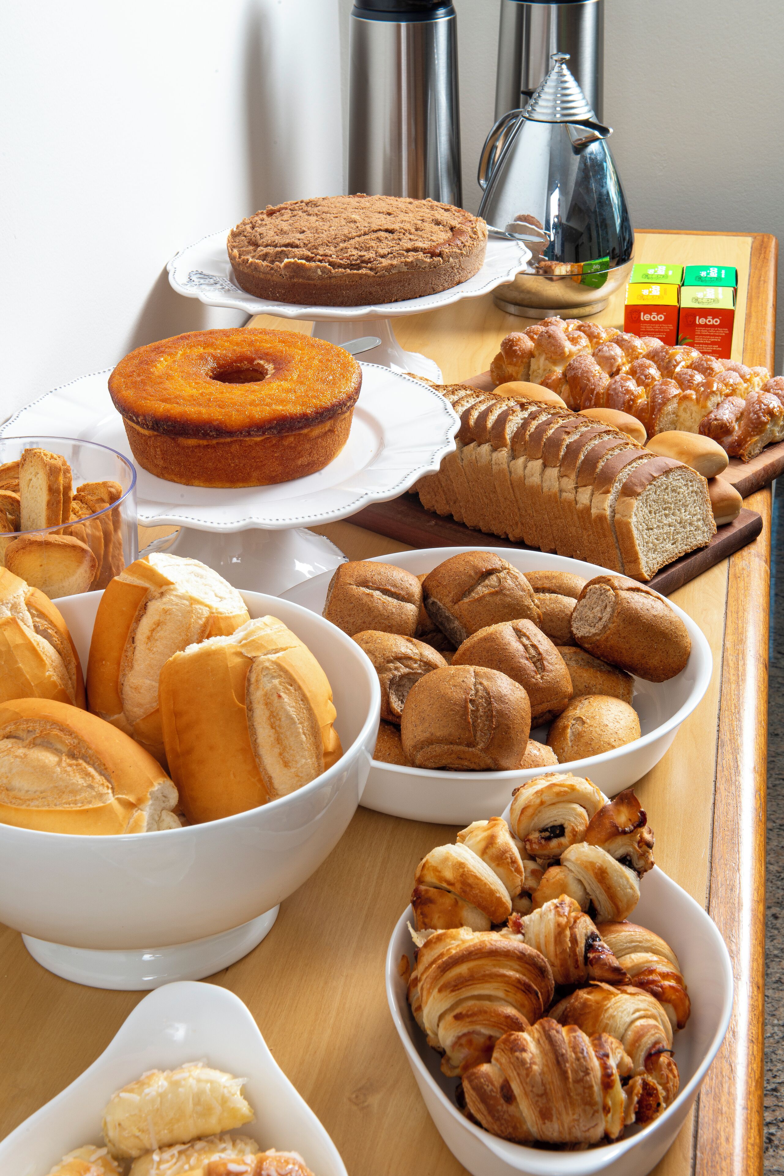 Eine Auswahl an Backwaren, darunter Kuchen, Brot und Gebäck, auf einem Holztisch angerichtet.