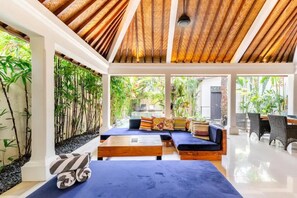 Relax in this stylish space with a large sofa, wooden coffee table, and bamboo plants.