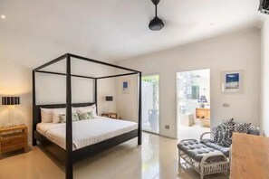 Relax in this serene bedroom with a four-poster bed, bedside tables, and a sliding glass door leading to an outdoor area.