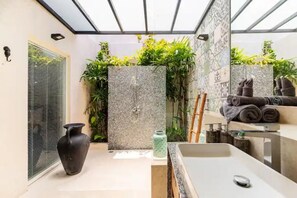 Bathroom features a large sink, dark vase, and patterned tiles.