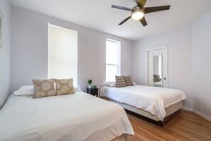 A bedroom with two beds, a ceiling fan, and a door with a mirror. - ENTIRE BUILDING-Walk to Lincoln Park or The Beach! (Chicago)