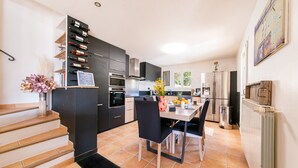 Una cocina moderna con comedor, que incluye una escalera, armarios negros y piso de baldosas.