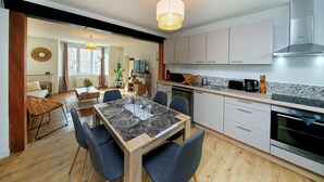 Una cucina moderna con mobili bianchi, un'area pranzo con tavolo decorato e un'ampia finestra.
