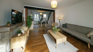 Un soggiorno moderno con un tavolino in legno, un divano grigio e una TV fissata a una parete in marmo.