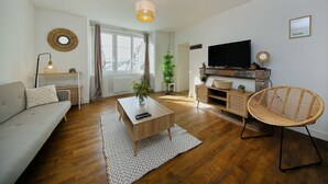 Un soggiorno moderno con divano, tavolino, televisore e poltrona in vimini.