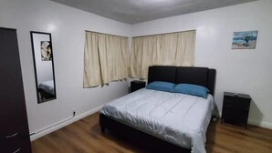 Een slaapkamer met een bed, een kast, een nachtkastje en een spiegel.