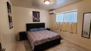 A bedroom with a bed, a nightstand, a wall-mounted air conditioner, and a window with curtains. - 2 bedroom 1 bathroom, Cozy home (South El Monte)