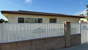 A single-story house with a beige exterior, a white fence, and a brick foundation. - 2 bedroom 1 bathroom, Cozy home (South El Monte)