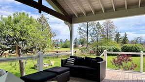 An outdoor patio with wicker furniture and a view of a grassy area with trees. - Cottage On Waterfowl Pond/Dog Friendly Fenced Yard (Somers)
