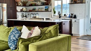 A modern kitchen with dark wood cabinets, a white island, and pendant lighting. - Cottage On Waterfowl Pond/Dog Friendly Fenced Yard (Somers)