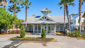 A large, modern building with a prominent tower and large windows, surrounded by palm trees and well-maintained landscaping.