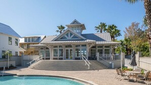 A resort with a swimming pool, outdoor seating, and a covered area with steps leading to a building.