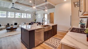 A modern kitchen with a large island, stainless steel appliances, and pendant lighting.