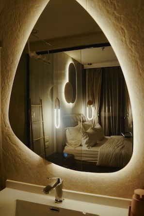 Un baño con un espejo grande, un lavabo y una zona de ducha.