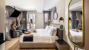 Een moderne hotelkamer met een groot bed, nachtkastje, spiegel en uitzicht.