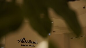 Een kamer met een bank, een klein bijzettafeltje en een bordje aan de muur met de tekst 'AllenBeach SMART HOTEL'.