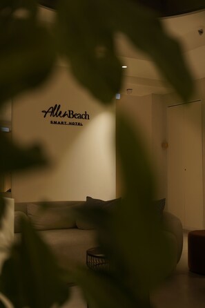 Habitación con sofá, una mesita auxiliar y un cartel en la pared que dice 'AllenBeach SMART HOTEL'.