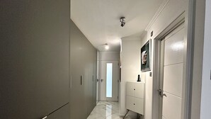Ein Korridor mit Marmorboden, einem Schrank, einer Kommode und einer Tür mit einem gerahmten Bild.