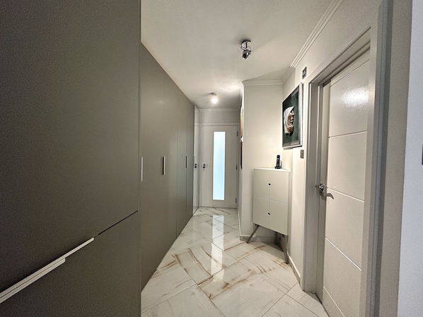 A hallway with a marble floor, a wardrobe, a cabinet, and a door with a framed picture. - Central London Apartment - Euston area of zone 1 London.
(London)