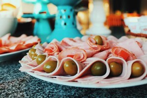 A plate of sliced ham and olives arranged on a table. - Pousada Baleia Azul (Rio das Ostras)