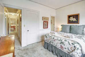 A bedroom with a bed, a wooden dresser, a door, and a hallway leading to another room. - Central & Ornate Sewanee Home w/ Screened-In Porch (Sewanee)