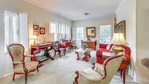 A spacious living room with a fireplace, a red sofa, and a wooden coffee table. - Central & Ornate Sewanee Home w/ Screened-In Porch (Sewanee)