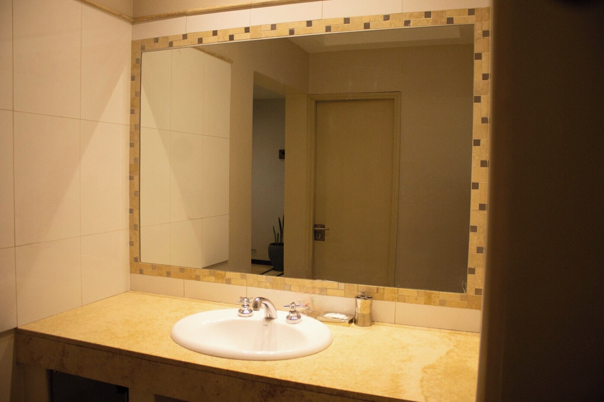 A bathroom with a large mirror, a sink, and a door.