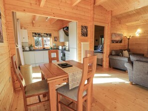 A cozy wooden cabin interior with a dining area, kitchen, and living room.