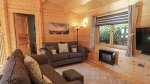 A cozy cabin interior with a sofa set, a fireplace, and a painting on the wall. - Little Lodge (Newton Stewart)