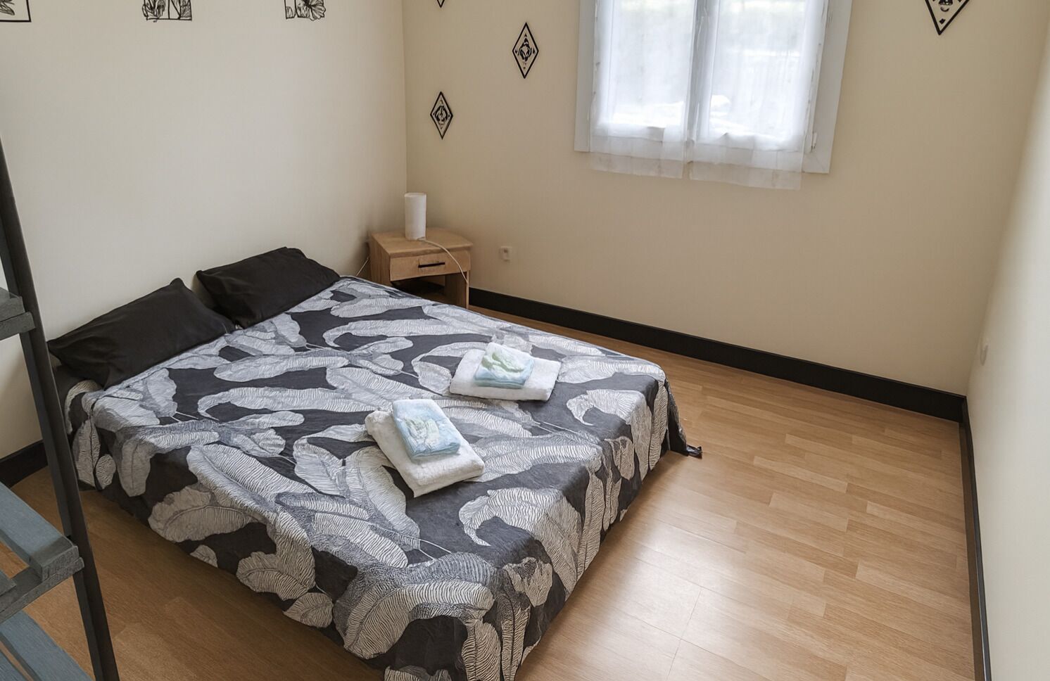 Une chambre à coucher comprenant un lit, une table de chevet, une fenêtre et un mur agrémenté d’éléments décoratifs.