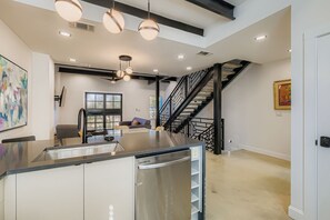 Une cuisine moderne dotée d’un îlot central, d’appareils électroménagers en acier inoxydable et de luminaires suspendus.