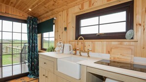 Een houten keuken in een chalet, met een groot raam, een spoelbak en een houten aanrecht.