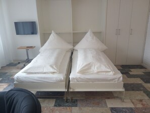A room with two beds, a small table, and a wardrobe. - Enjoy a relaxing stay at the RosenRot am Meer 2 vacation apartment   (Borkum)