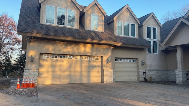 A two-story house with a garage, stone foundation, and a driveway. - Peaceful Retreat (Minneapolis)
