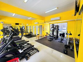 Un gimnasio con cintas de correr, máquinas de pesas y un espejo grande.