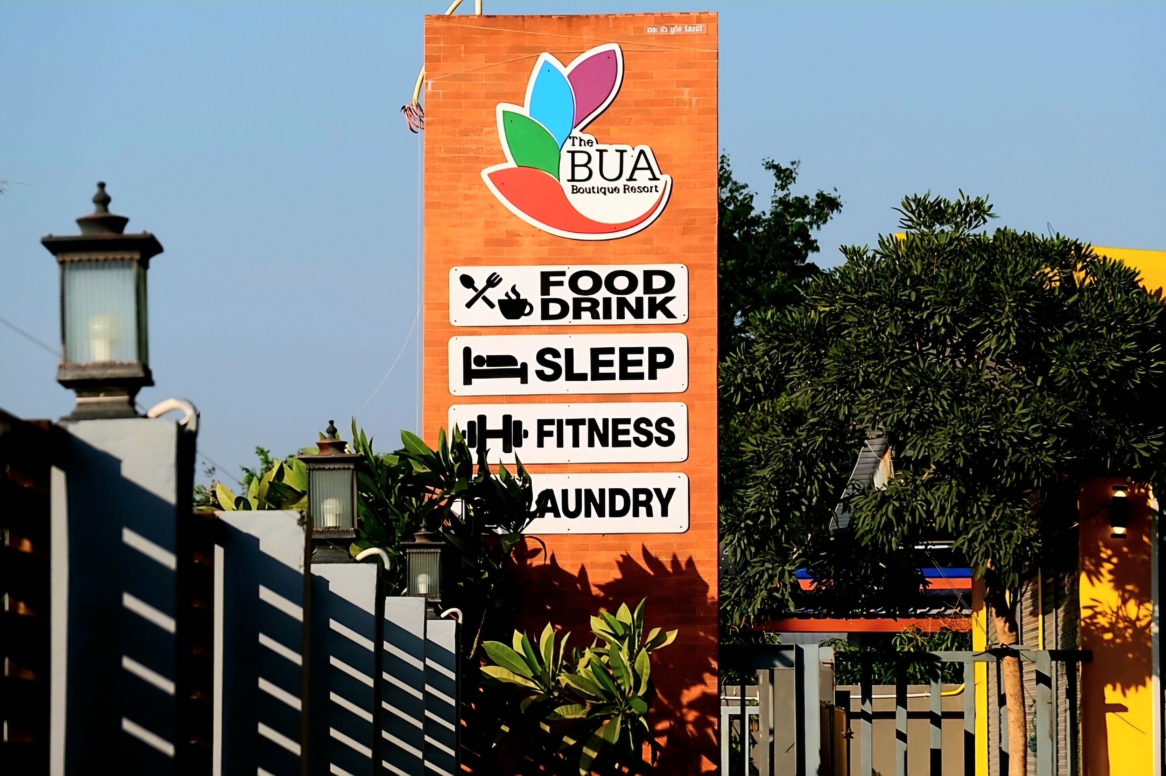 A sign for The BUA Boutique Resort with amenities including food, drink, sleep, fitness, and laundry services.