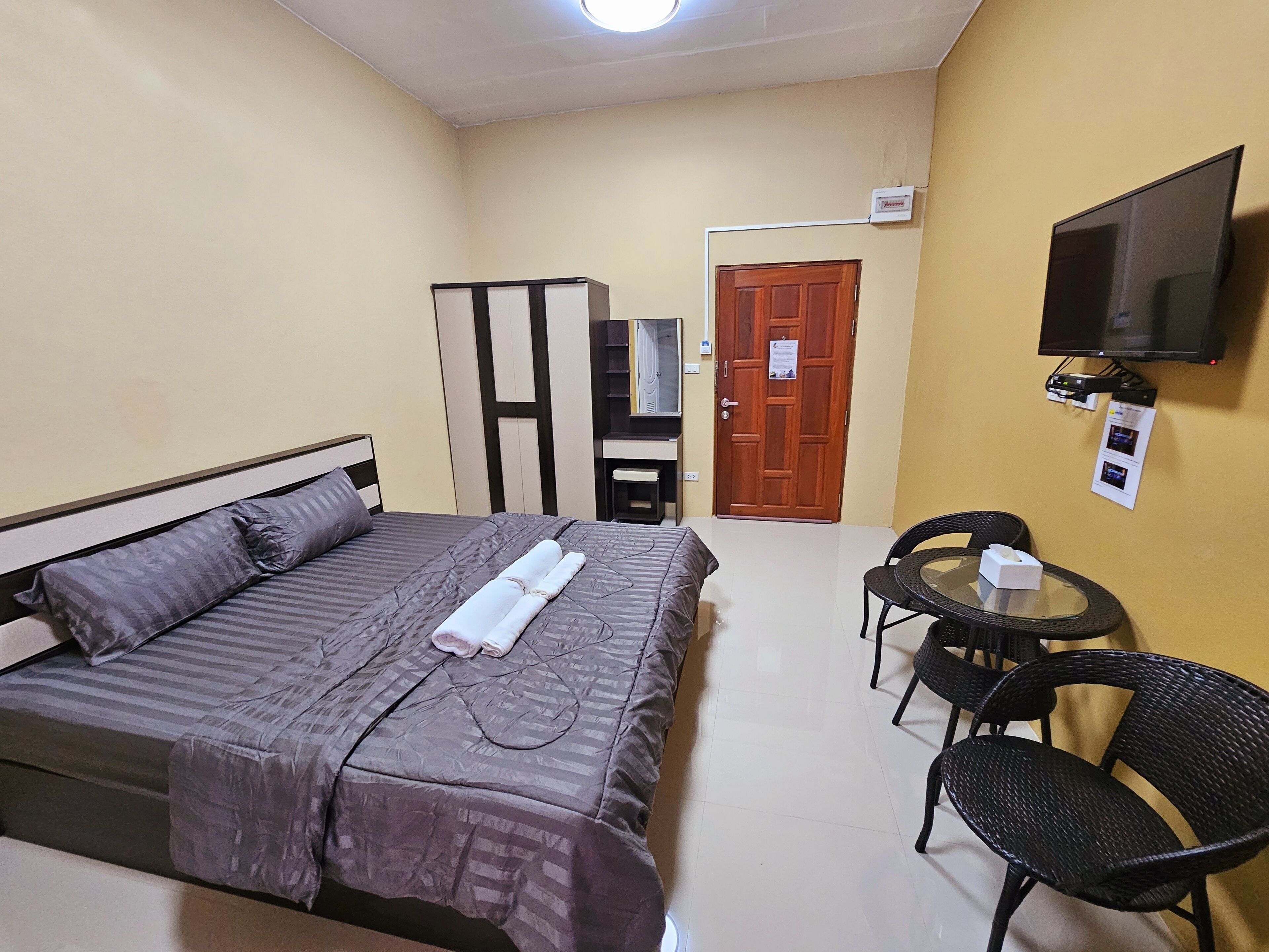 A hotel room with a bed, a TV, a desk, and a chair.