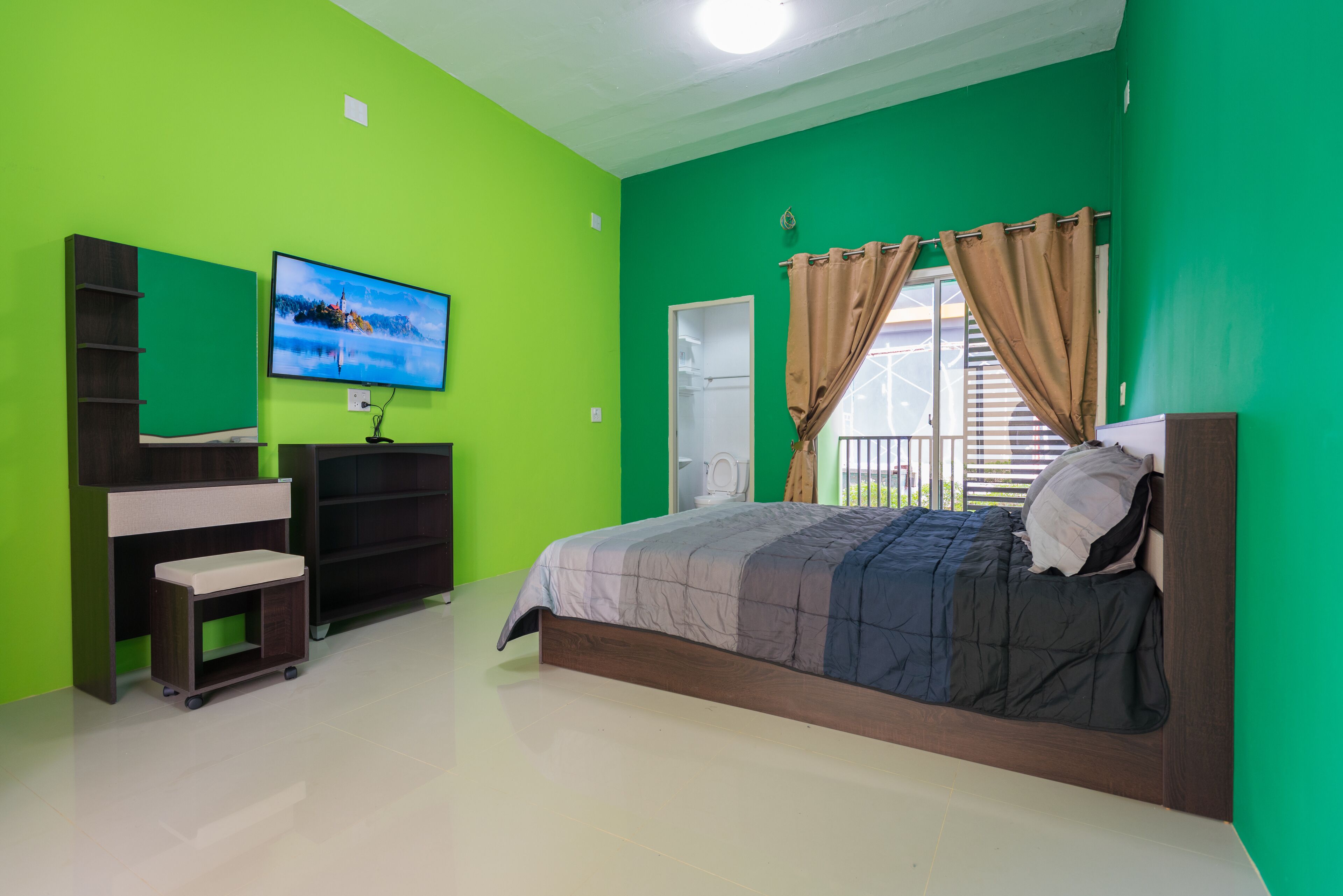 A bedroom with a bed, a television, a wardrobe, and a window with curtains.