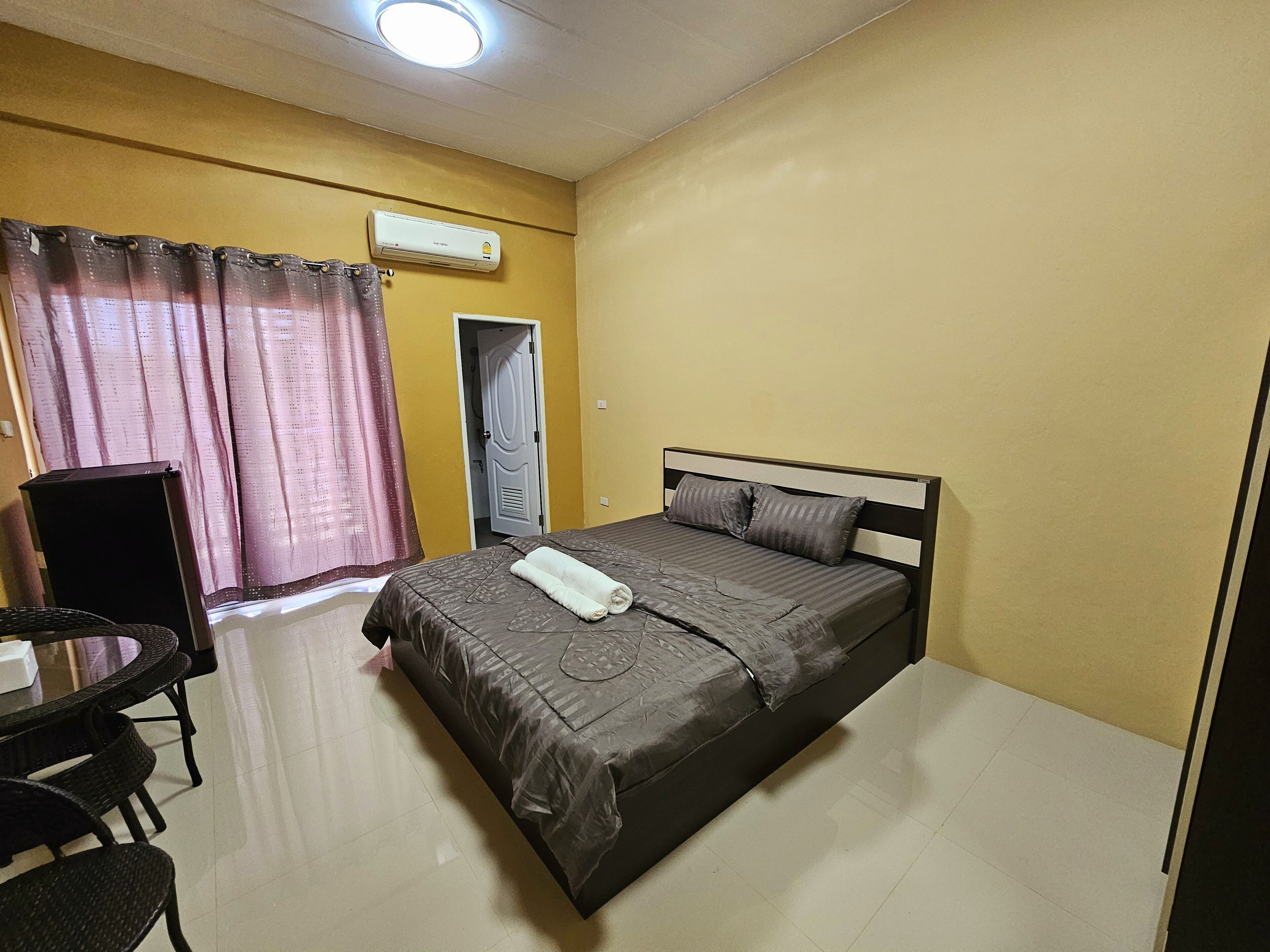 Una habitación de hotel con cama, escritorio, silla, aire acondicionado y puerta.