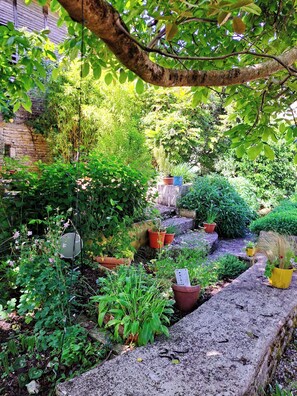 A garden with various potted plants and a stone pathway. - Former forge, leisure area with pool (Marigny)