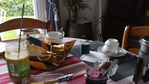 Une table de petit-déjeuner avec une variété d’aliments, notamment un pot de confiture, un verre de jus de fruits, un bol de céréales et une assiette avec une pâtisserie.
